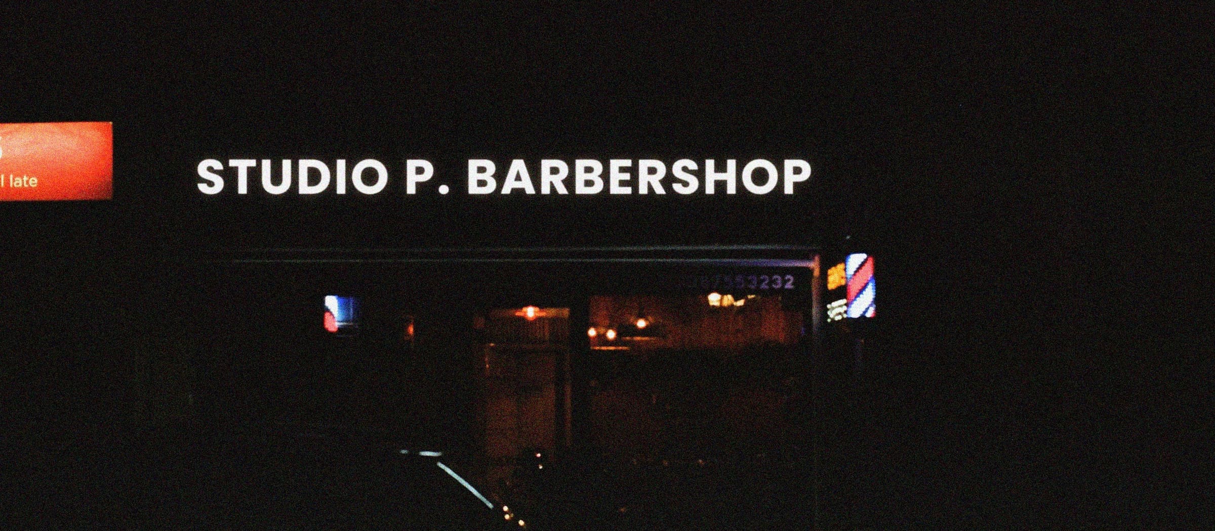 The Studio P. Barbershop storefront at night, its sign lit above the shop window